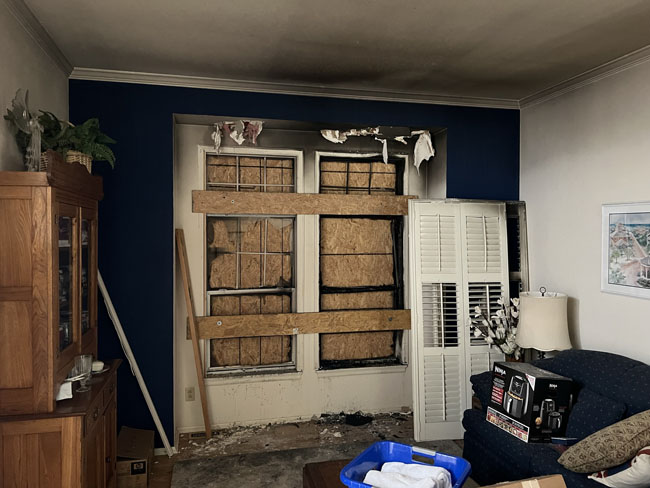 Living room with boarded up window after fire damage
